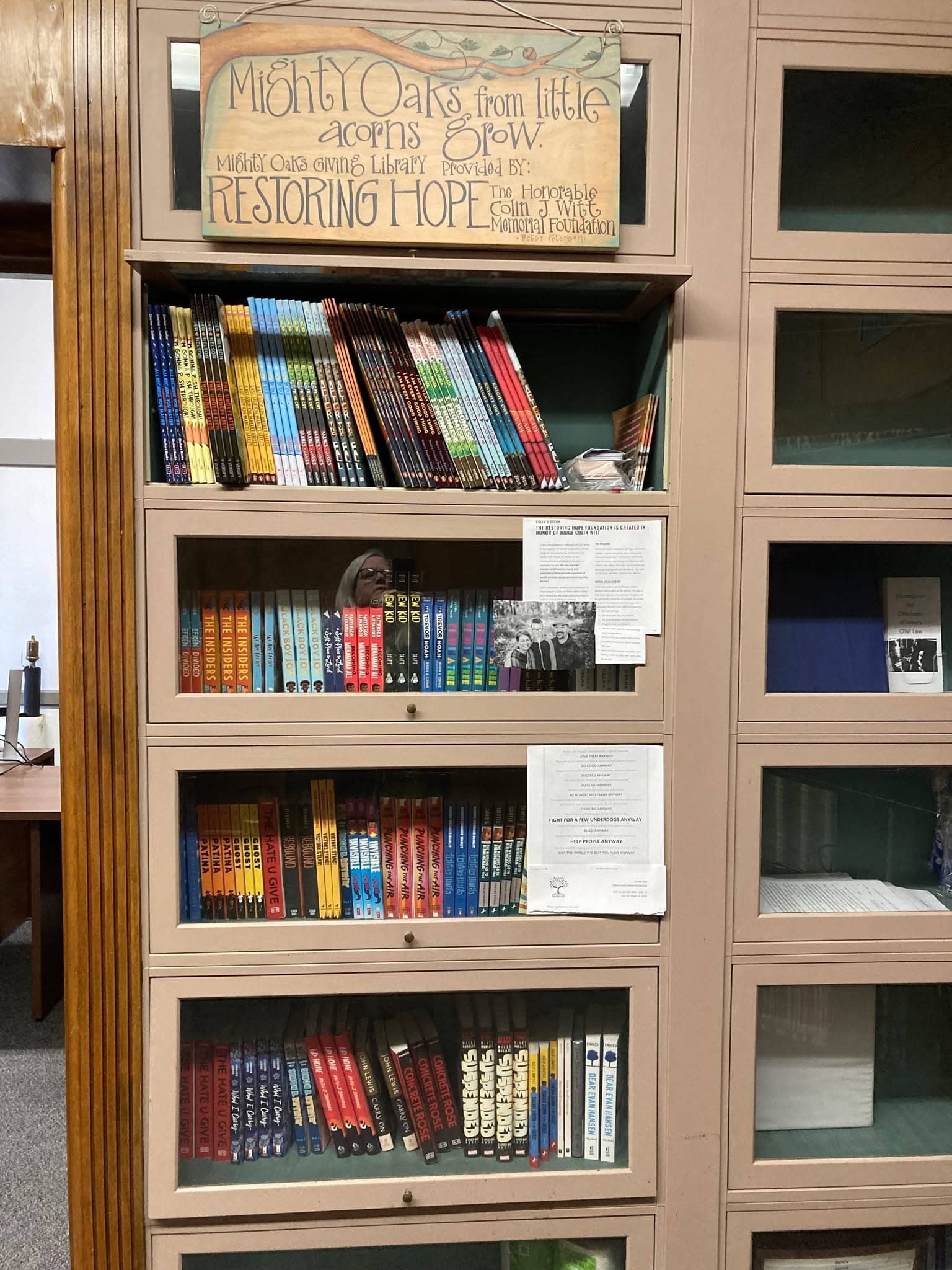 Mighty Oaks Giving Library case in a courthouse, with Colin's story posted inside